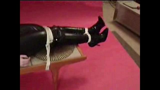 Red Head JADE TAPE GAGGED & BOUND TO COFFEE TABLE IN BLACK PVC CATSUIT & HIGH HEELED BOOTS Gay Blackhair - 1